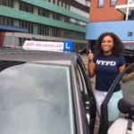 Geslaagde leerling poseert bij lesauto met All-in-One bord
